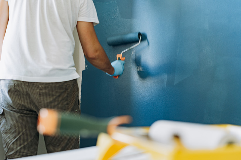 caucasian bearded man painting wall with paint roller. Painting apartment, renovating home
